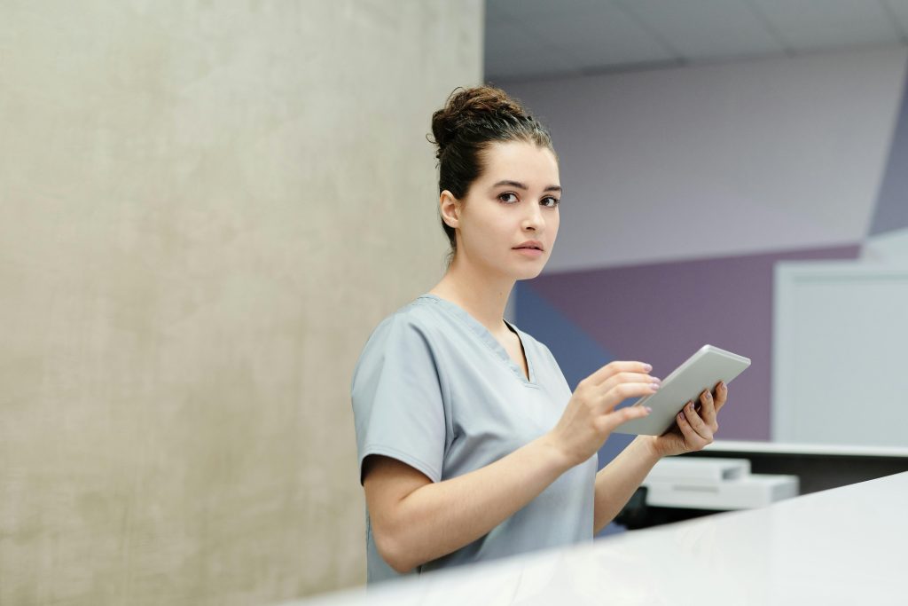 Professional receptionist using a tablet device at a modern office reception desk.